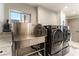 Modern laundry room with stainless steel dog wash basin and front loading washer and dryer, creating a functional space at 7880 Dana Point Ct, Las Vegas, NV 89117