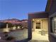 Backyard at dusk featuring stone patio, covered dining, and desert-friendly landscaping at 2568 Dirleton Pl, Henderson, NV 89044