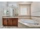 Elegant bathroom features a soaking tub, vanity, and a glass block window at 2568 Dirleton Pl, Henderson, NV 89044