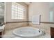 Bathroom featuring a large soaking tub and a decorative glass block window at 2568 Dirleton Pl, Henderson, NV 89044