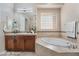 Bright bathroom featuring a soaking tub, decorative glass block window, and a large vanity with dual sinks at 2568 Dirleton Pl, Henderson, NV 89044