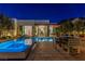 A modern outdoor pool with an attached spa and a dining table for entertaining guests at 371 Tranquil Peak Ct, Henderson, NV 89012