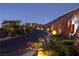 An illuminated entryway curves uphill, showcasing the community's sign and lush, landscaped surroundings at dusk at 371 Tranquil Peak Ct, Henderson, NV 89012