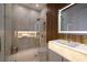 Sleek bathroom with a glass-enclosed shower, wood-paneled wall, and a unique illuminated sink at 665 Overlook Rim Dr, Henderson, NV 89012