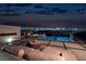 Rooftop deck with outdoor seating, fireplace, and pool with stunning city views at twilight at 665 Overlook Rim Dr, Henderson, NV 89012