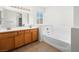 Bathroom with a bathtub, double vanity, and light brown cabinets at 9307 Bondeno St, Las Vegas, NV 89123