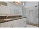 Modern bathroom features dual sinks, a spacious shower with stone accents, and bright lighting at 10300 Bent Brook Pl, Las Vegas, NV 89134