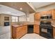 Open kitchen with wood cabinets and black appliances, seamlessly connected to the living area at 5855 Valley Dr # 2045, North Las Vegas, NV 89031