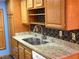 Kitchen with wood cabinets, granite counters, and double sink at 6681 Bubbling Brook Dr # A, Las Vegas, NV 89107