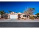 Tan house with a two-car garage and well-maintained landscaping at 9800 Dusty Winds Ave, Las Vegas, NV 89117