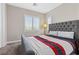 This bedroom features a large window, carpet flooring, plantation shutters, and a stylish upholstered headboard at 10729 Beecher Park Ave, Las Vegas, NV 89166