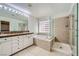 Elegant bathroom with double sinks, a soaking tub, and a walk-in shower at 1624 Ravanusa Dr, Henderson, NV 89052