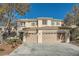 Two-story house with beige exterior, three-car garage, and landscaping at 1624 Ravanusa Dr, Henderson, NV 89052