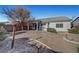 Wide view of the home's backyard and covered patio with a hardscape, rock, and some shrubbery at 5919 Pavilion Lakes Ave, Las Vegas, NV 89122