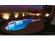 Backyard with a freeform pool, fire pit, lounge seating, brick perimeter wall, desert landscaping, and evening lighting at 5919 Pavilion Lakes Ave, Las Vegas, NV 89122