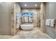 Luxurious bathroom with freestanding tub, glass-enclosed shower, and marble tile at 609 Sleeping Dragon Dr, Henderson, NV 89012