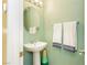 Small bathroom with pedestal sink, round mirror, and green walls at 9904 Garamound Ave, Las Vegas, NV 89117