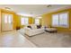 Bright living room with tiled floors, white sofas, and yellow walls at 9904 Garamound Ave, Las Vegas, NV 89117