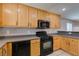 Kitchen featuring light wood cabinets, black appliances, and tile floors at 3396 Villa Fiori Ave, Las Vegas, NV 89141