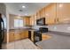 Well-lit kitchen with tile flooring, cabinets, black appliances, and a window over the sink at 3396 Villa Fiori Ave, Las Vegas, NV 89141