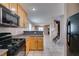 Open kitchen with wood cabinets, tile flooring, black appliances, and view to living area at 3396 Villa Fiori Ave, Las Vegas, NV 89141