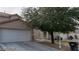 Beige house with a two-car garage and mature tree in front at 5987 Stone Hollow Ave, Las Vegas, NV 89156