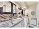 Well-lit bathroom with double sinks, marble countertops, and decorative mosaic tiles at 12745 Fairfield Ave, Henderson, NV 89044