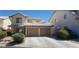Two-story house with tan exterior, two-car garage, and landscaping at 7555 Glowing Ember Ct # 201, Las Vegas, NV 89130