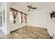 Minimalist bedroom with sleek ceiling fan, three windows dressed in dark gray sheers and wood-look tile flooring at 284 Crimson Edge St, Henderson, NV 89012