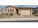 One-story house with tan exterior, brown shutters, and brick paver driveway at 470 Pebble Run Ave, Henderson, NV 89011