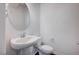 Clean bathroom with oval mirror, pedestal sink, and toilet at 10306 Coastline Creek Ct, Las Vegas, NV 89141