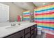 Bathroom with rainbow shower curtain and dark vanity at 1937 Shanon Michelle Ave, North Las Vegas, NV 89031