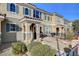 Tan two-story townhome with gray door and small front patio with seating at 2077 Via Firenze, Henderson, NV 89044