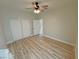 Bright bedroom featuring wood-look floors, ceiling fan, and double doors to closet at 2560 Tahachapi Ave, Pahrump, NV 89048