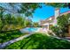 A refreshing backyard pool with lush landscaping, a brick-paved patio, and a well-manicured lawn, perfect for outdoor enjoyment at 56 Sawgrass Ct, Las Vegas, NV 89113