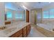 Bright bathroom with large mirror, dual sinks, marble counters, shower, and soaking tub at 56 Sawgrass Ct, Las Vegas, NV 89113