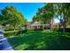 A view of the front of the home shows manicured landscaping and mature trees on the property at 56 Sawgrass Ct, Las Vegas, NV 89113