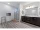 Bathroom with a large mirror, double sinks, dark wood cabinets, and a glass-enclosed shower at 3540 Valley Lily St, North Las Vegas, NV 89032