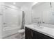 Clean bathroom featuring a tub with white tile surround, a dark vanity, and gray wood-look flooring at 3540 Valley Lily St, North Las Vegas, NV 89032