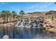 Beautiful waterfall feature surrounded by palm trees and lush landscaping at 4 Via Centrale # 1, Henderson, NV 89011