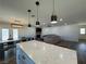 Kitchen island with white cabinets and quartz countertop, overlooking living room at 5640 Judith Resnik Ct, Las Vegas, NV 89103