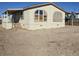 Tan mobile home with covered porch and large windows, situated on a lot with dirt landscaping at 6214 Mount Rainier Ave, Las Vegas, NV 89156