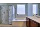 Bright bathroom featuring a tub with a window view and separate shower with glass enclosure and seashell shower curtain at 2429 Anderson Park Dr, Henderson, NV 89044