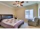 Bedroom with ceiling fan, light colored walls, a large bed with a quilted bedspread, and an upholstered armchair at 2429 Anderson Park Dr, Henderson, NV 89044