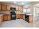 Kitchen with wood cabinets, black appliances, and tile floor at 7491 Speedwell Cavern St, Las Vegas, NV 89139