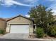 Tan house with white garage door and mature tree at 8970 College Green St, Las Vegas, NV 89148