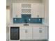 Elegant bar area with white cabinetry, a wine fridge, and stylish blue tile backsplash at 1131 Blackhorn St, Pahrump, NV 89048