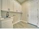 The laundry room features white cabinets, a stainless steel sink, and wood-look tile flooring at 1131 Blackhorn St, Pahrump, NV 89048
