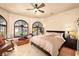 Main bedroom with arched windows, seating area, and ceiling fan at 2204 Glenbrook Way, Las Vegas, NV 89117