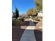 Park-like community walkway with stone groundcover, green shrubs, and mature trees under a clear blue sky at 3025 Sunrise Bay Ave, North Las Vegas, NV 89031